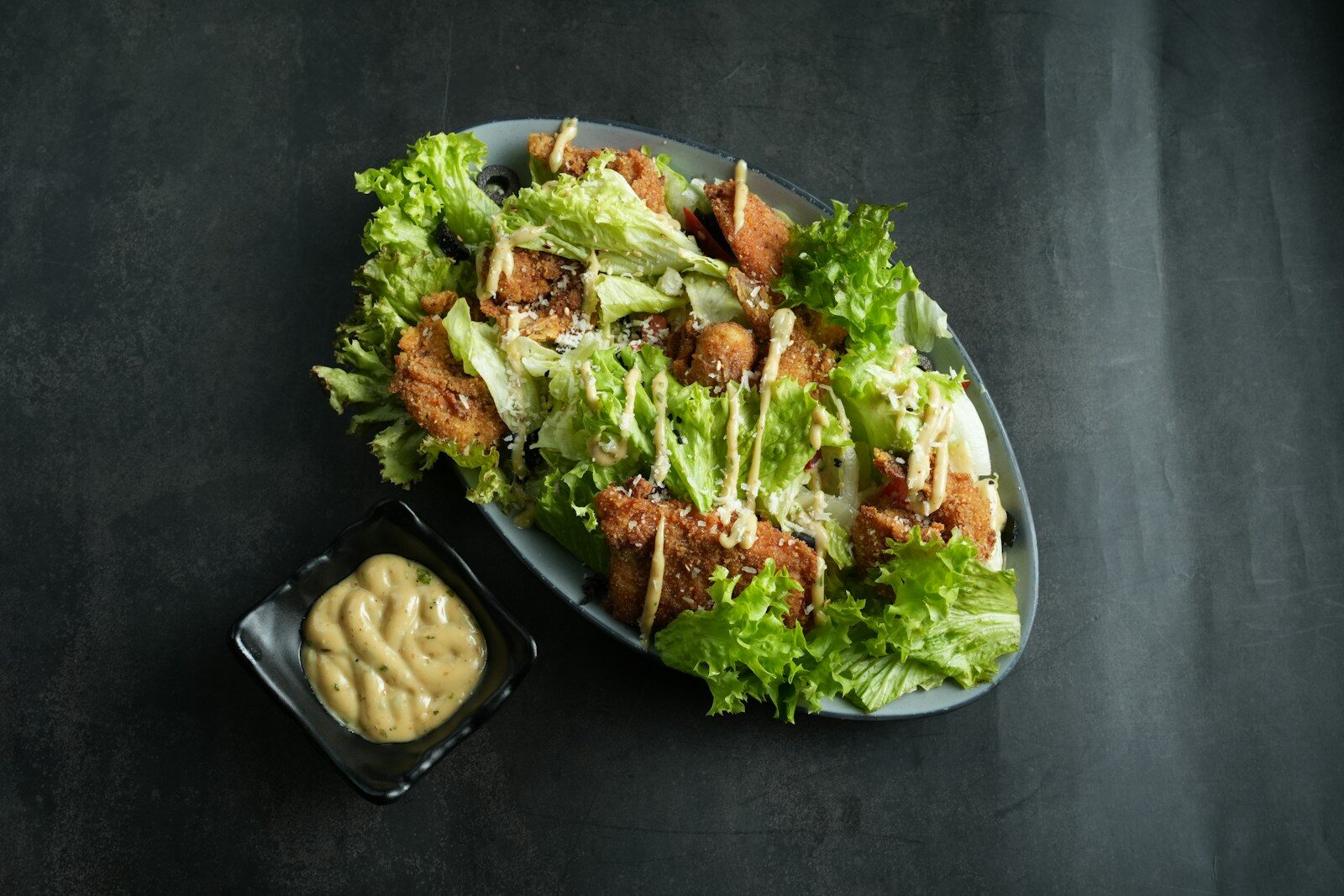 a plate of salad with dressing on the side